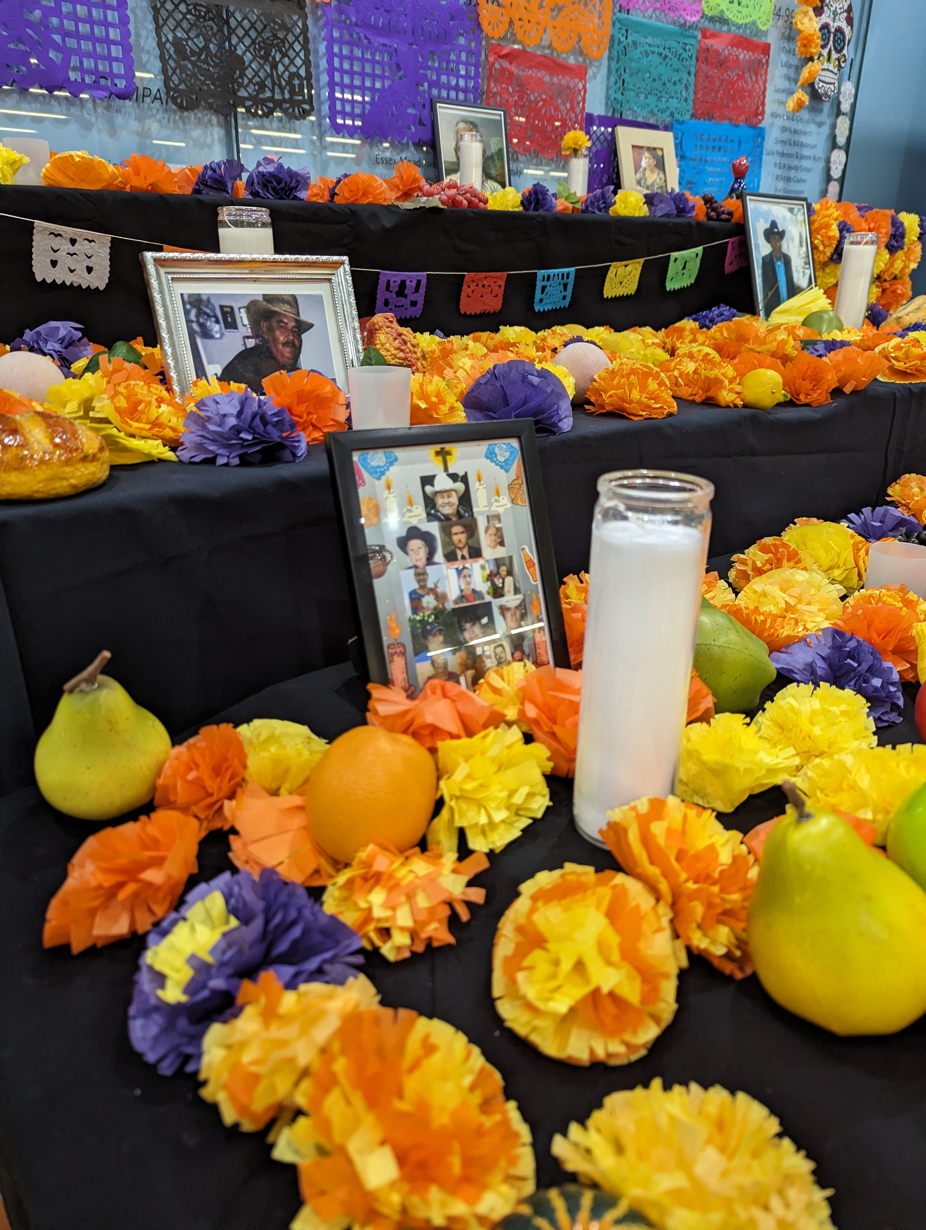 Ofrenda with paper marigolds, cut paper, photographs, candles, and food