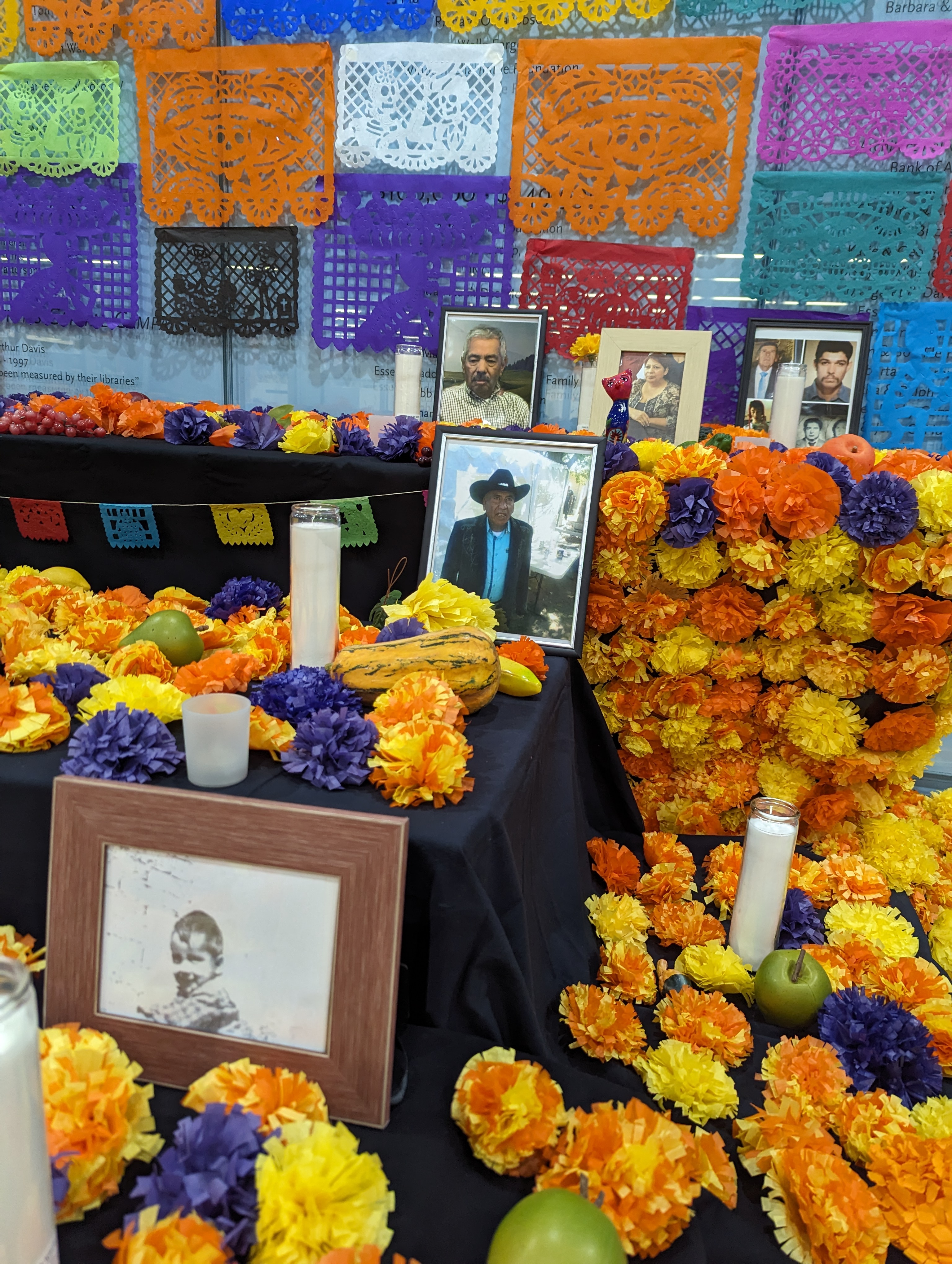 Ofrenda with paper marigolds, cut paper, photographs, candles, and food