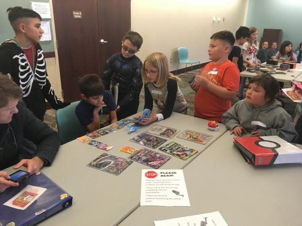 Photo of kids at a table playing pokemon cards