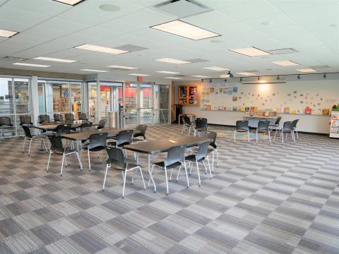 East Side Meeting Room with rectangular tables, chairs, large whiteboard, and chairs lined up against glass wall