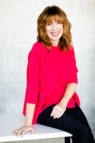 Nancy  Davis Kho sitting and smiling wearing a red top