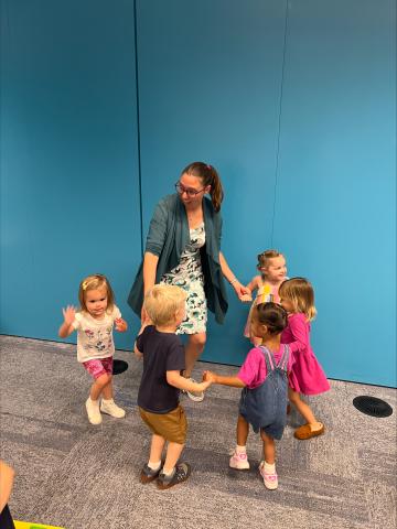 Sam Reid dances in a circle with a group of kids