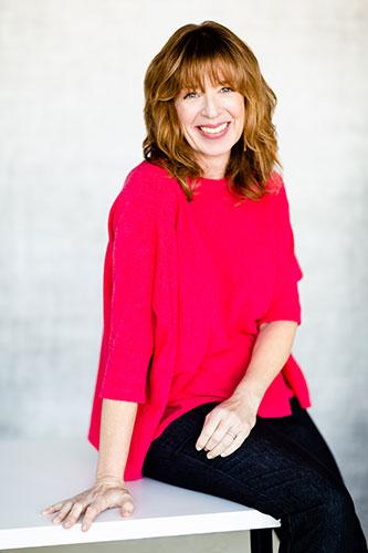 Nancy  Davis Kho sitting and smiling wearing a red top