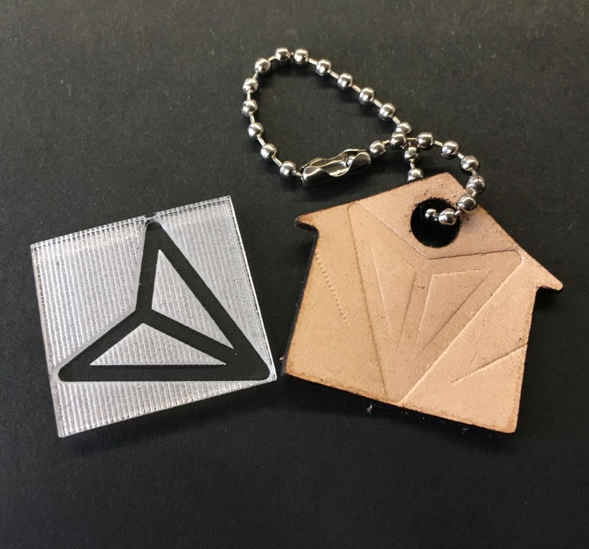 Image of debossing stamp made of clear acrylic and a debossed leather keychain.