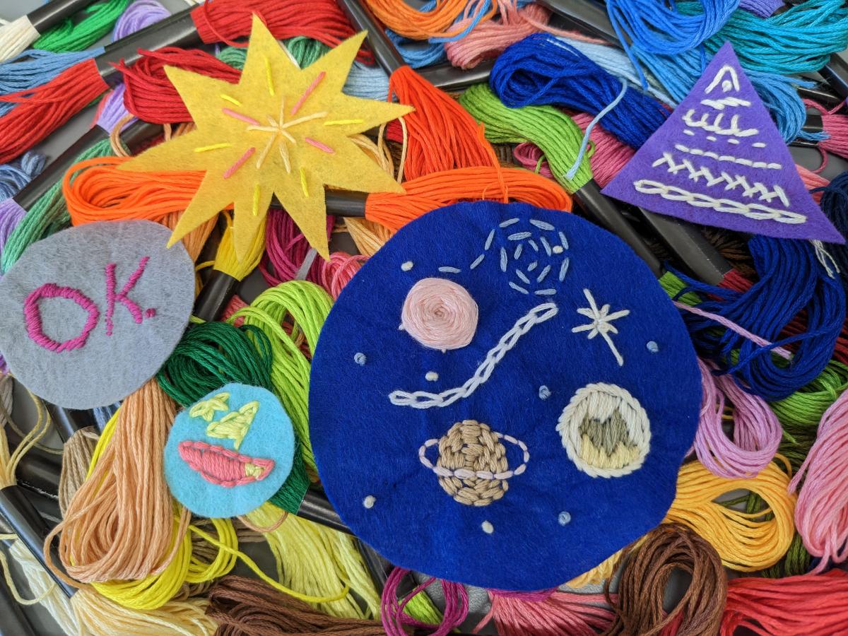 a few embroidered patches sitting on a pile of embroidery floss