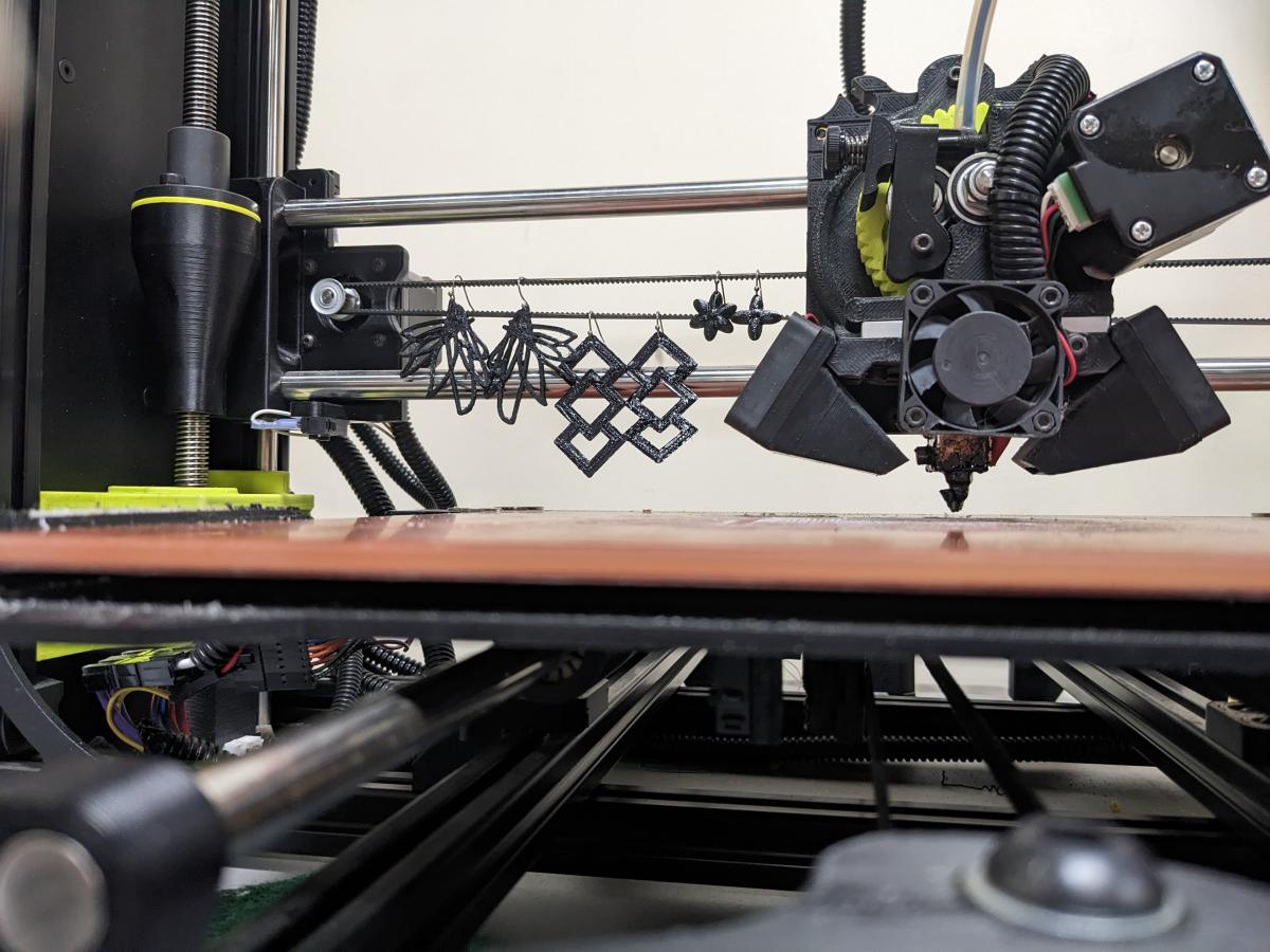 3D printed earrings hanging from a bar on the 3D printer