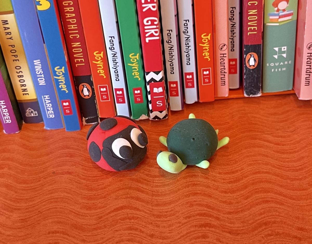Image of a small foam ladybug and small foam turtle in front of books